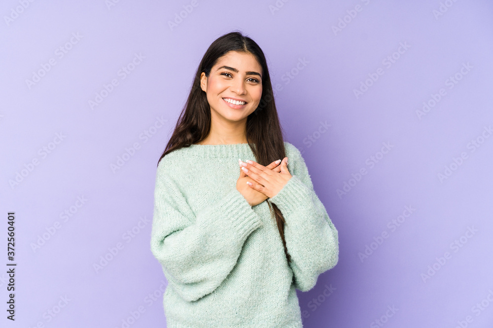 Young indian woman isolated on purple background has friendly expression, pressing palm to chest. Love concept. Young indian woman isolated on purple background has friendly expression, pressing palm to chest. Love concept.