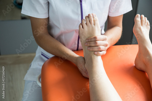 Hands of female physiotherapist massaging the foot of a woman photo