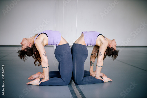 Ballet dancer bending over backwards in front of mirror at studio photo