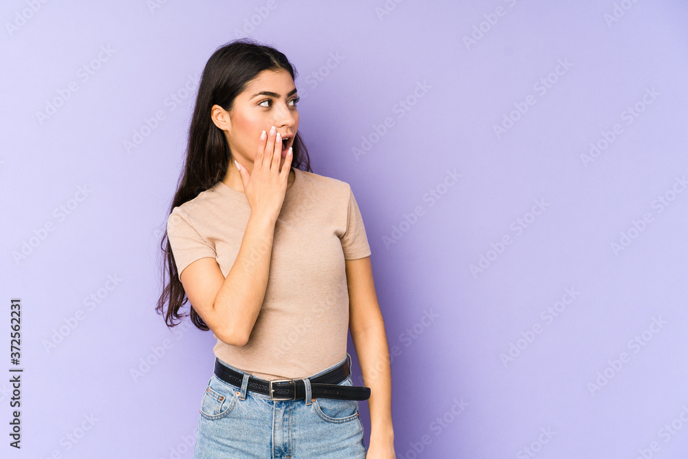Young indian woman isolated on purple background being shocked because of something she has seen. Young indian woman isolated on purple background being shocked because of something she has seen.