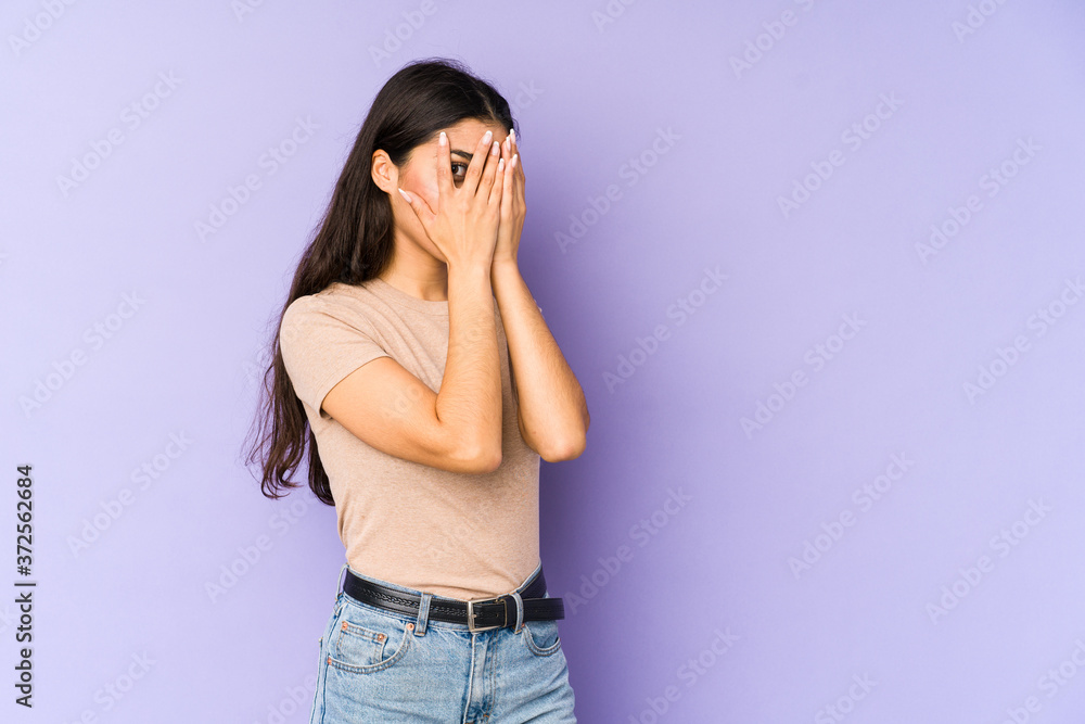 Young indian woman isolated on purple background blink through fingers frightened and nervous. Young indian woman isolated on purple background blink through fingers frightened and nervous.