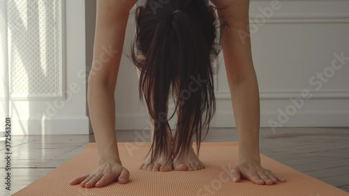 Young adult woman stretching and practicing yoga on a mat at home photo