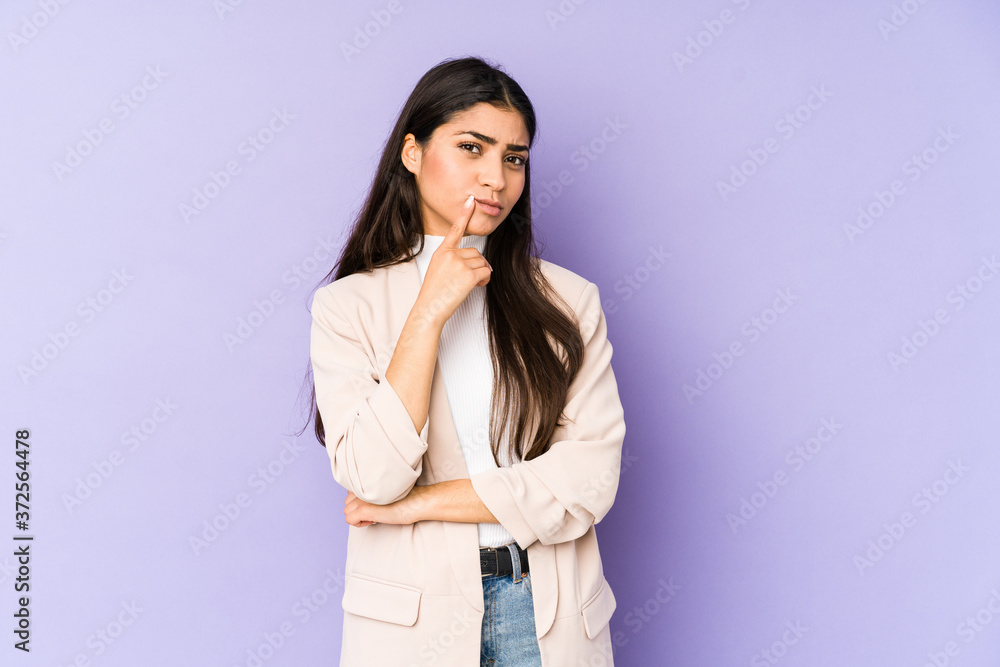 Young indian woman isolated on purple background looking sideways with doubtful and skeptical expression. Young indian woman isolated on purple background looking sideways with doubtful and skeptical expression.