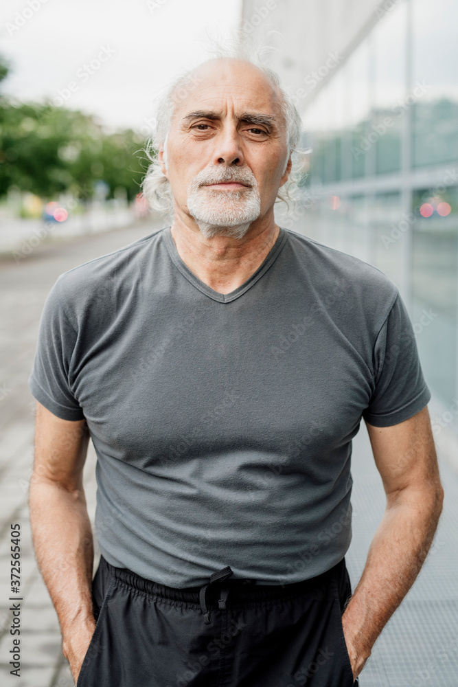 Confident senior man with hands in pockets standing in city Confident senior man with hands in pockets standing in city