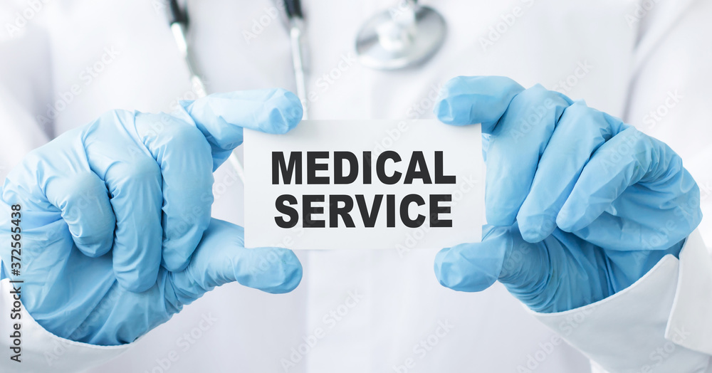 close-up of a doctor's hands hold a card with with medical service text. close-up of a doctor's hands hold a card with with medical service text.