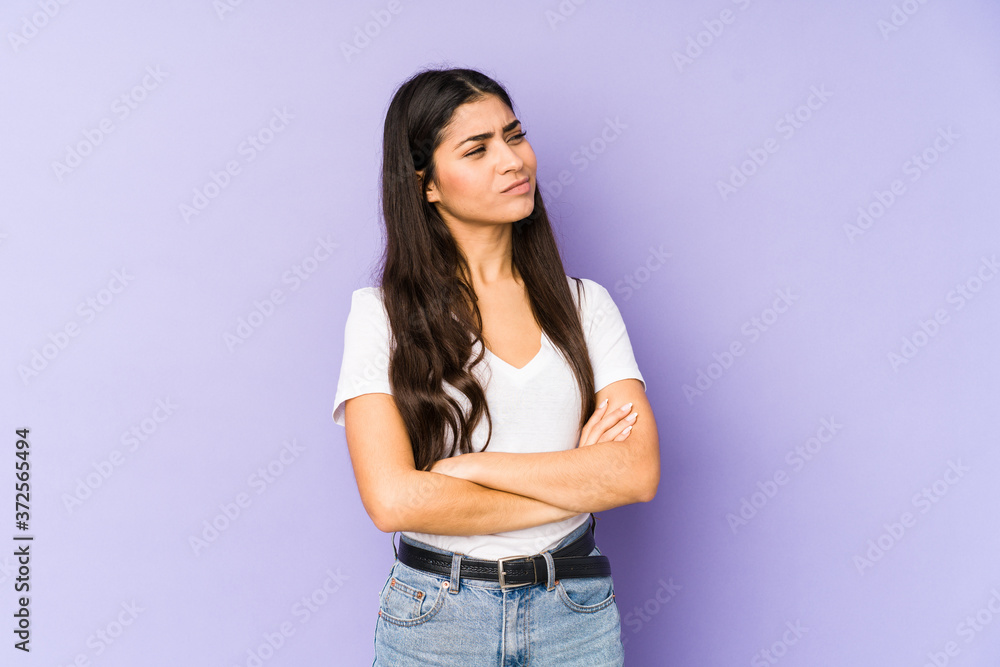 Young indian woman isolated on purple background suspicious, uncertain, examining you. Young indian woman isolated on purple background suspicious, uncertain, examining you.