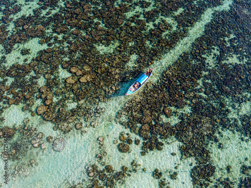 Thailand, Satun Province, Ko Lipe, Aerial view of fishing boat moored at rocky shore photo