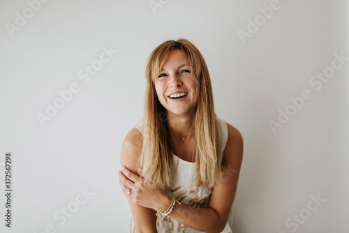 Happy beautiful woman standing against white wall at home photo
