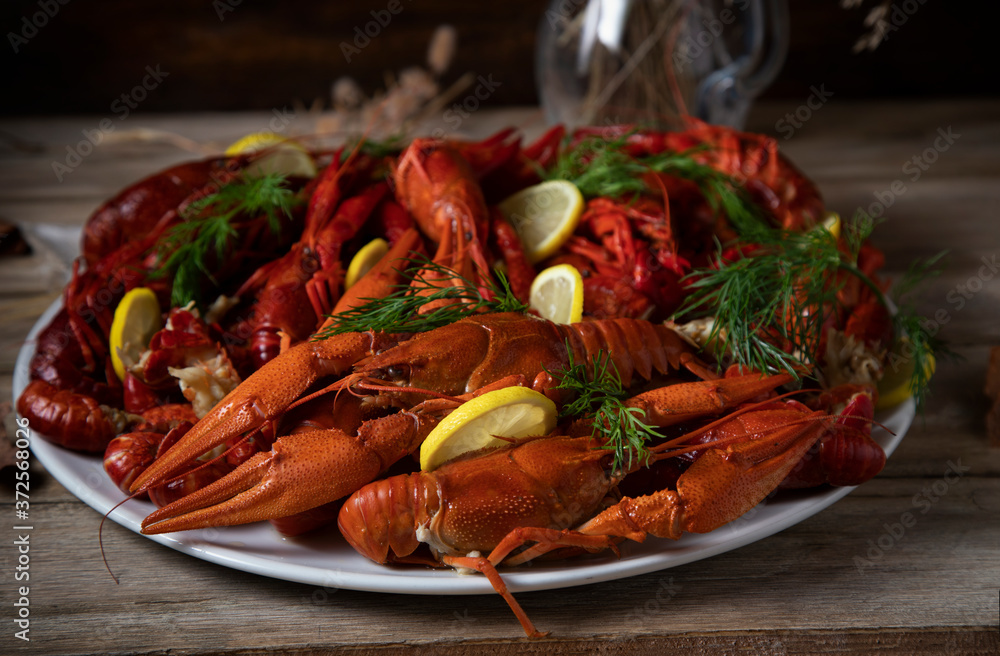 Boiled crayfish with dill and lemon on a white plate standing on a wooden table
Boiled crayfish with dill and lemon on a white plate standing on a wooden table