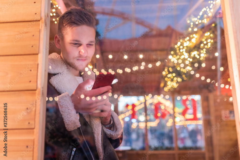 Young man using smart phone in store amusement park seen through window Young man using smart phone in store amusement park seen through window