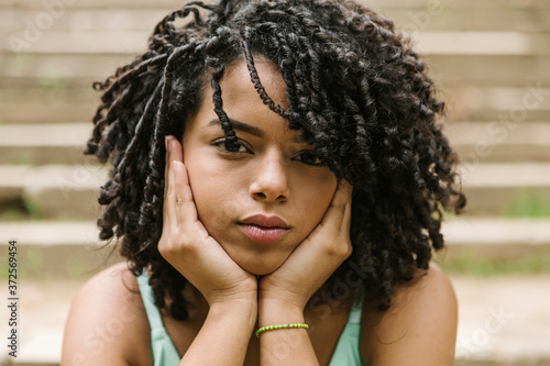 Portrait of curly young woman with hands on chin