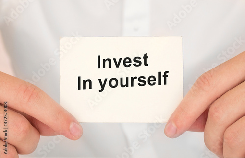 Man's hands take a card with words Invest in yourself, finance and business concept.
