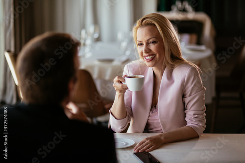 Beautiful businesswoman dressed in the suit drinking coffee. Businessman and businesswoman enjoying in the restaurant.