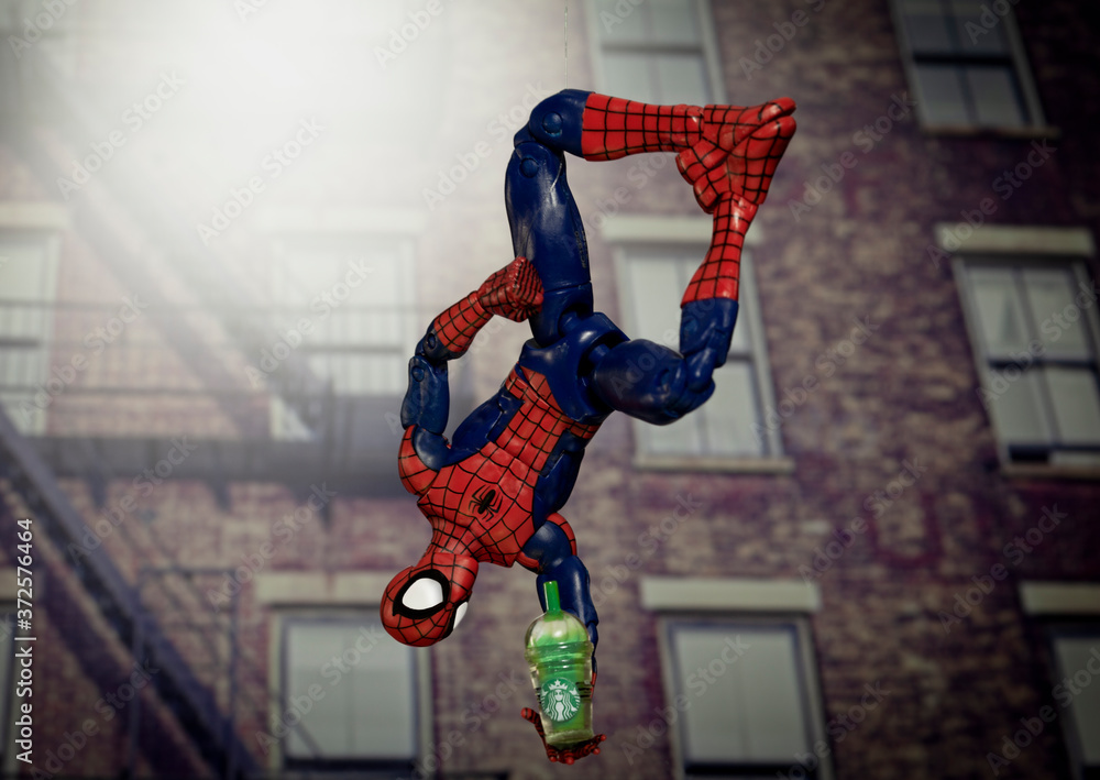 Obraz premium NEW YORK USA, AUGUST 19 2020: superhero Spiderman hanging upside down from a web with a Starbucks Frappuccino - Hasbro Legends action figure