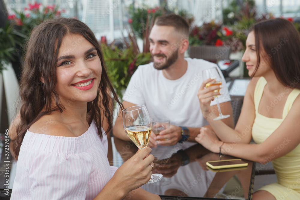 Charming happy woman smiling with a glass of wine in her hand, enjoying celebrating with her friends at the bar Charming happy woman smiling with a glass of wine in her hand, enjoying celebrating with her friends at the bar