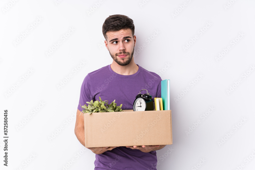Young caucasian man moving a new home isolated confused, feels doubtful and unsure. Young caucasian man moving a new home isolated confused, feels doubtful and unsure.