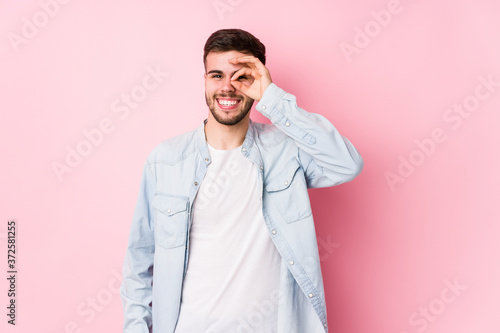 Young caucasian business man posing in a white background isolated excited keeping ok gesture on eye.< mixto >