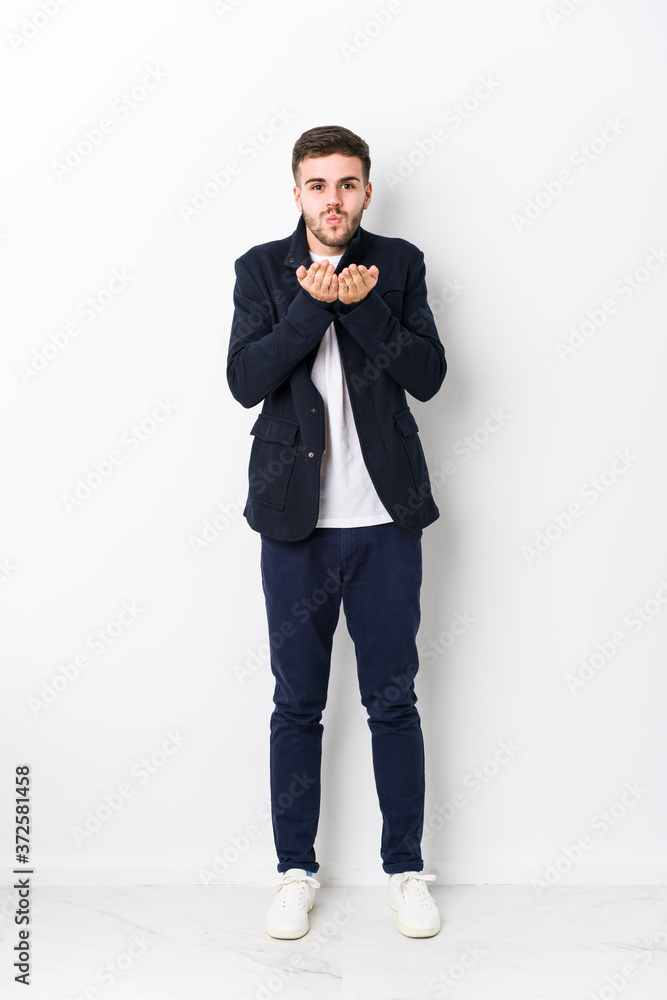 Full body young caucasian man isolated folding lips and holding palms to send air kiss.