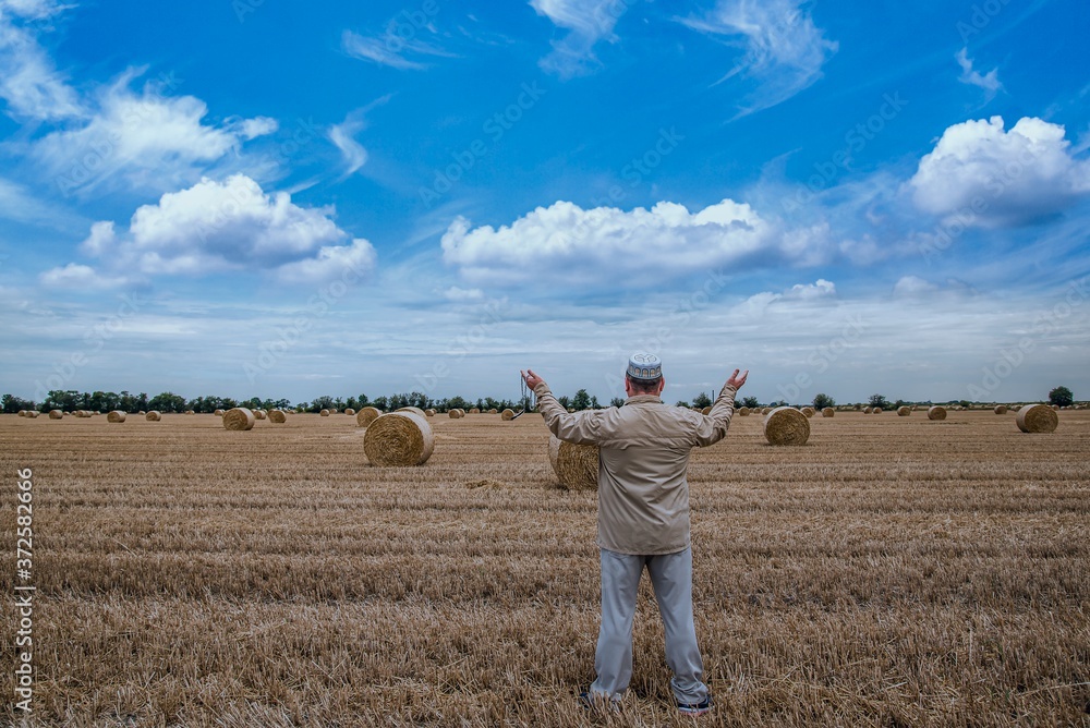 man prays in the field alone, hands to the sky man prays in the field alone, hands to the sky