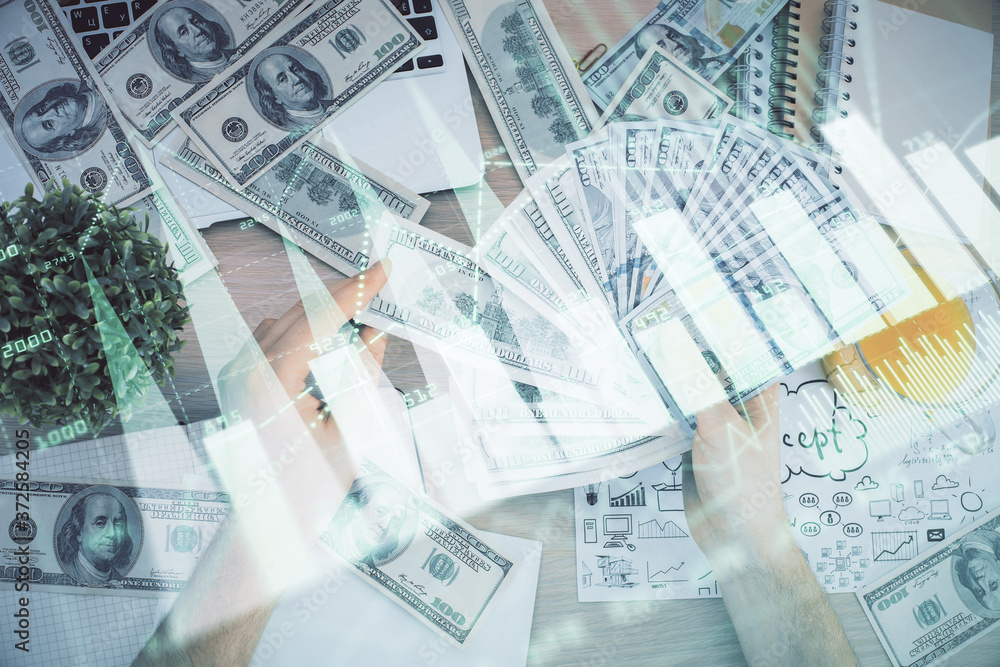 Fototapeta premium Multi exposure of financial graph drawing hologram and USA dollars bills and man hands. Analysis concept.