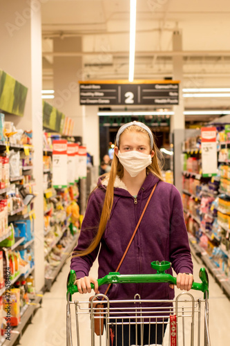 A girl wearing handmade face covering mask with shopping trolley at the supermarket during the COVID-19 pandemic