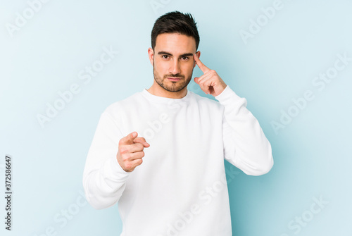 Young caucasian man isolated on blue background pointing temple with finger, thinking, focused on a task.