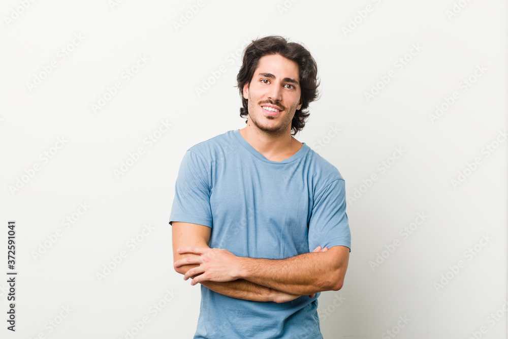 Young handsome man against a white background who feels confident, crossing arms with determination. Young handsome man against a white background who feels confident, crossing arms with determination.