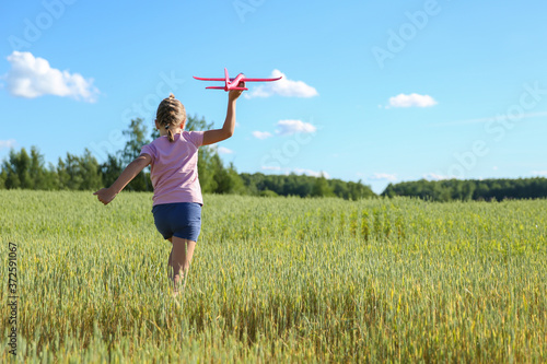 child playing with toy airplane glider in the field © Петр Смагин