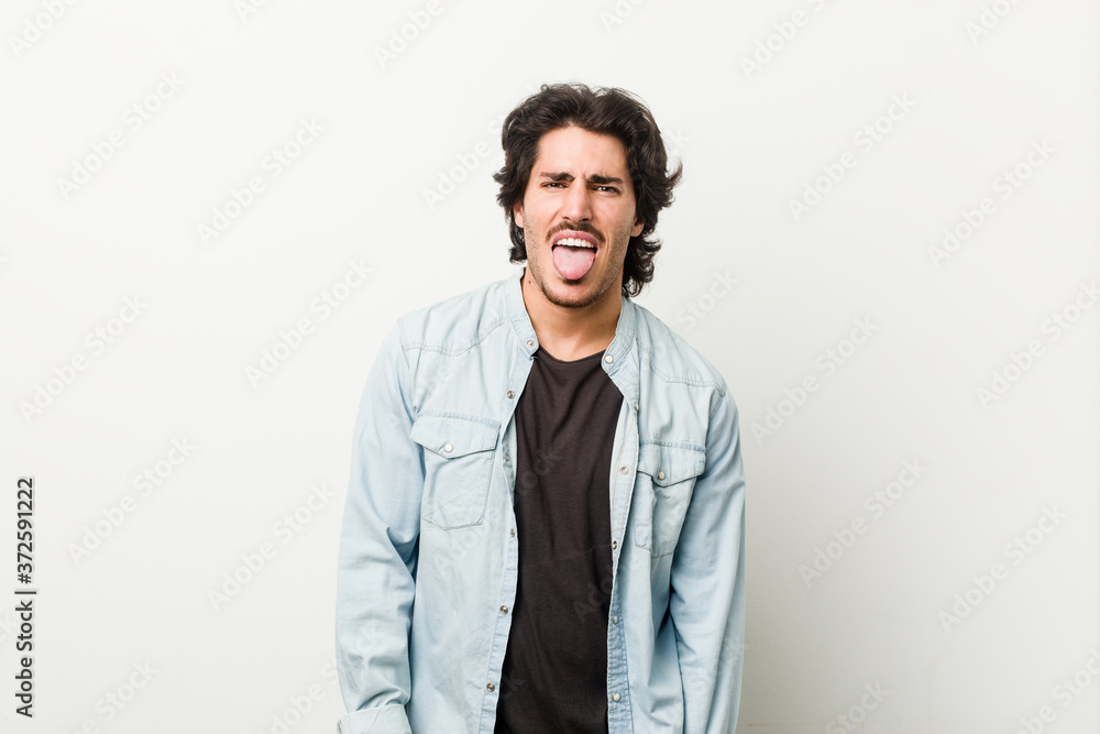 Young handsome man against a white background funny and friendly sticking out tongue. Young handsome man against a white background funny and friendly sticking out tongue.