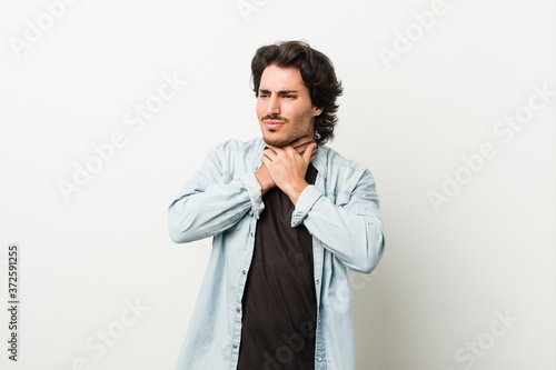 Young handsome man against a white background suffers pain in throat due a virus or infection. © Asier