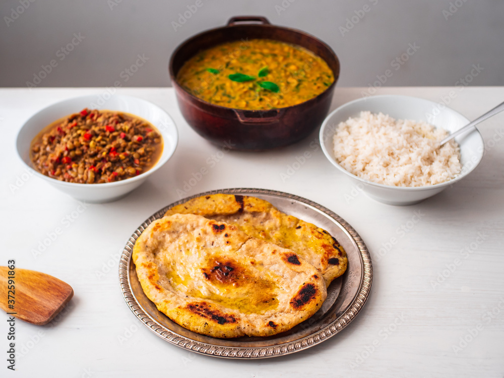 Vegetarian Vegan Indian Buffet of Chick Pea and Spinach Curry, White Rice, Lentil Dhal Stew and Naan Breads in Various Pots and Bowls on a White Background