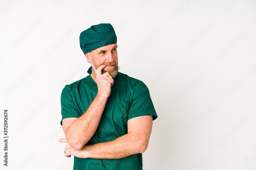 Surgeon senior man isolated on white background relaxed thinking about something looking at a copy space.
