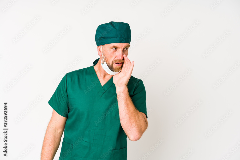 Surgeon senior man isolated on white background is saying a secret hot braking news and looking aside Surgeon senior man isolated on white background is saying a secret hot braking news and looking aside