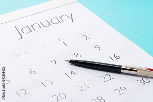 Close-up of a calendar and pen on a blue background