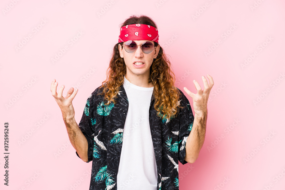 Young hippie caucasian man isolated upset screaming with tense hands.