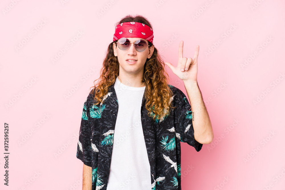 Young hippie caucasian man isolated showing a horns gesture as a revolution concept.