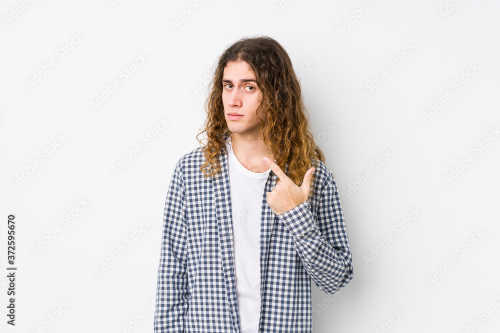 Young long hair man posing isolated pointing with finger at you as if inviting come closer. Young long hair man posing isolated pointing with finger at you as if inviting come closer.