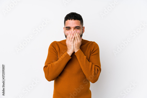 Young latin man against a white background isolated laughing about something, covering mouth with hands.