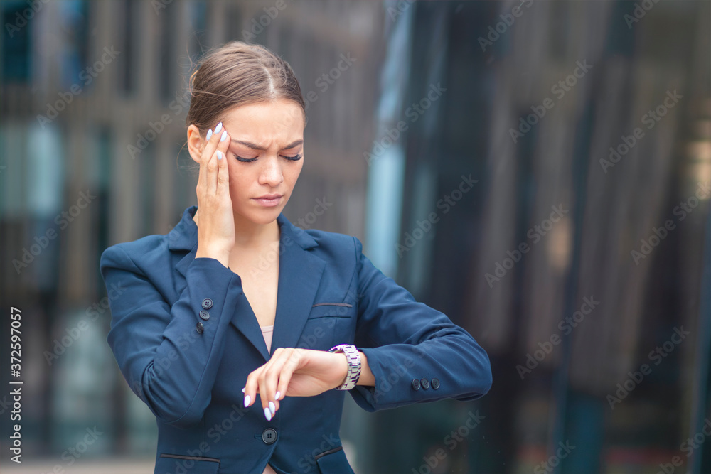 Beautiful tired exhausted businesswoman in hurry looking at her wrist watch, woman checking time on watches, rushing. Young attractive pretty lady suffering from headache, migraine. Girl touch temples