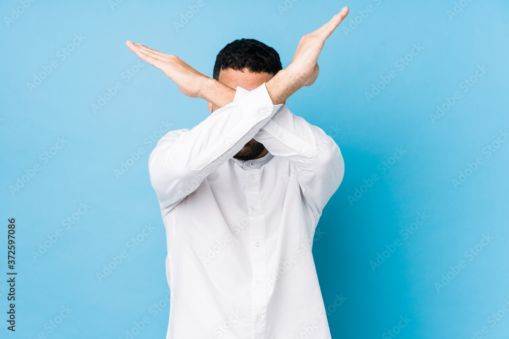 Young latin man against a blue background isolated keeping two arms crossed, denial concept. Young latin man against a blue background isolated keeping two arms crossed, denial concept.