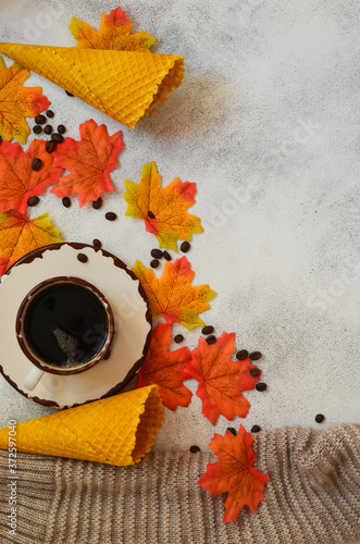 Autumn background with copy space for text and design. A cup of coffee, coffee beans waffle cones and autumn leaves. Cozy atmosphere and warm mood © Marina Shvedak