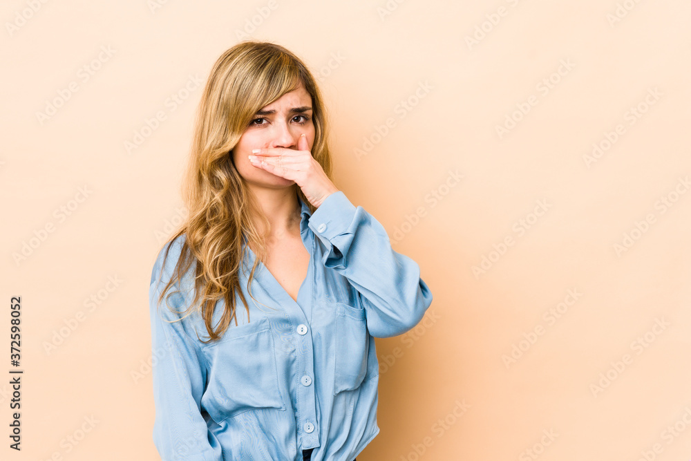 Young blonde caucasian woman covering mouth with hands looking worried.