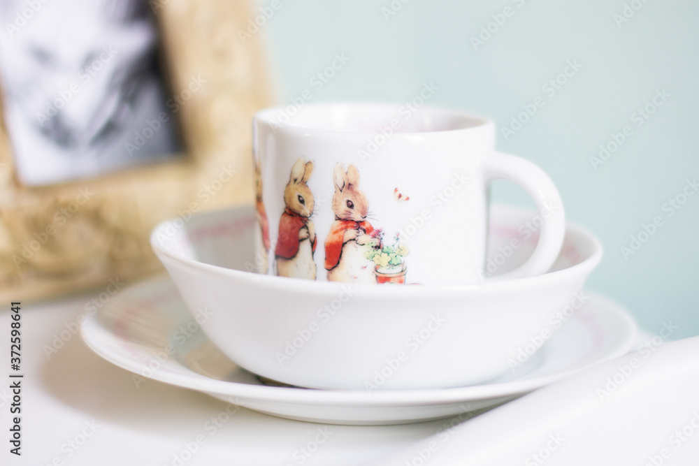 Tea cup with bunny illustration sitting inside white bowl Tea cup with bunny illustration sitting inside white bowl