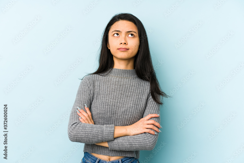 Young chinese woman isolated on a blue background tired of a repetitive task. Young chinese woman isolated on a blue background tired of a repetitive task.