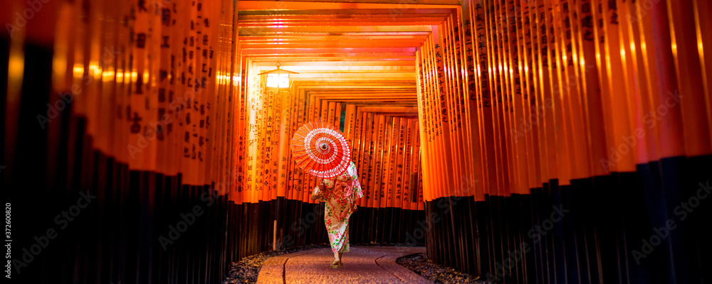 Naklejka premium Japanese girl in Yukata with red umbrella at Fushimi Inari Shrine