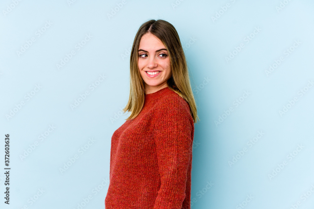 Young caucasian woman isolated on blue background looks aside smiling, cheerful and pleasant. Young caucasian woman isolated on blue background looks aside smiling, cheerful and pleasant.