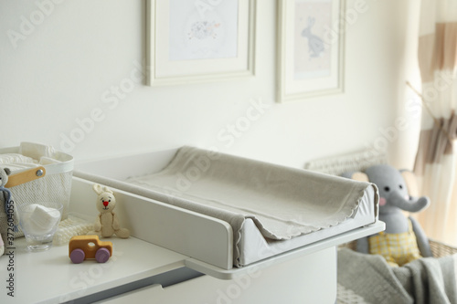 Modern changing table with toys and accessories in baby room