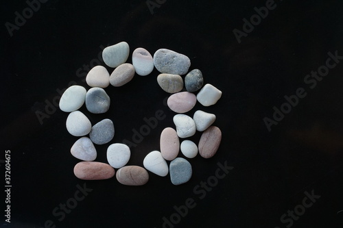 O letter shape of Pebble stones on dark background concepts. © muhammad