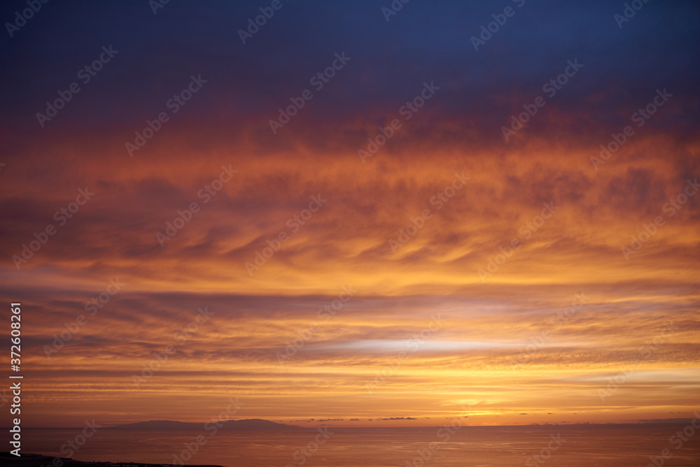 Back view of unrecognizable female tourist standing near car and taking photo of amazing sunset over ocean on mobile phone Back view of unrecognizable female tourist standing near car and taking photo of amazing sunset over ocean on mobile phone