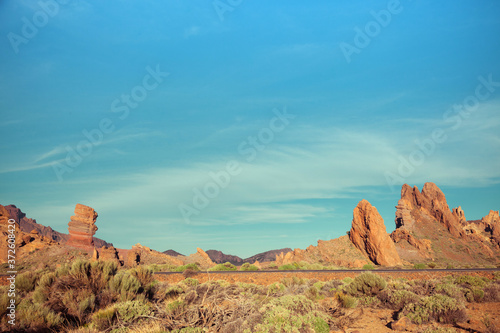 Scenery view of small shapeless mounts surrounded by green shrubs on dry terrain under picturesque cloudy sky in daylight photo